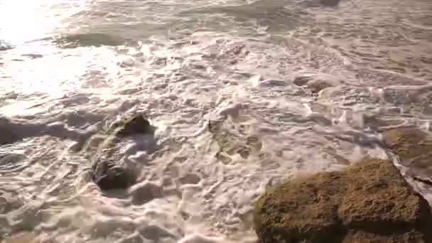 El agua del océano se rompe en las rocas en un día soleado brillante — Vídeos de Stock