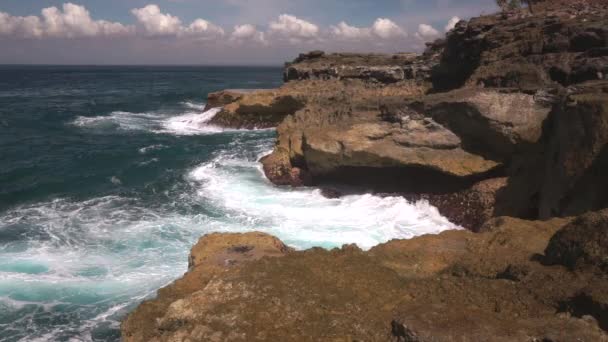 Ocean water breaks on rocks on bright sunny day — Stock Video