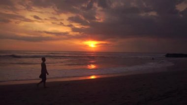 Adam gün batımında sahilde yürüyor