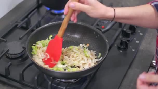 Nainen sekoittamalla sipulit ja vihreä paprika kuumalla pannulla — kuvapankkivideo