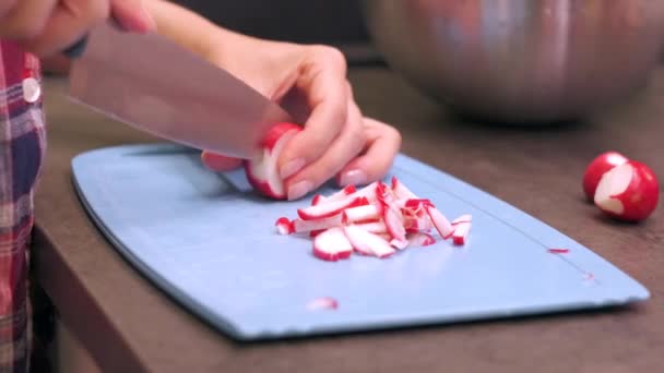 Young woman cuts radish on plastic cutting board — Stock Video