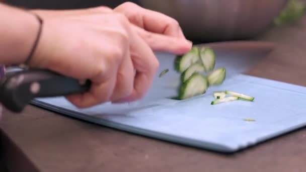 Young housewife slices cucumbers on plastic board — Stock Video