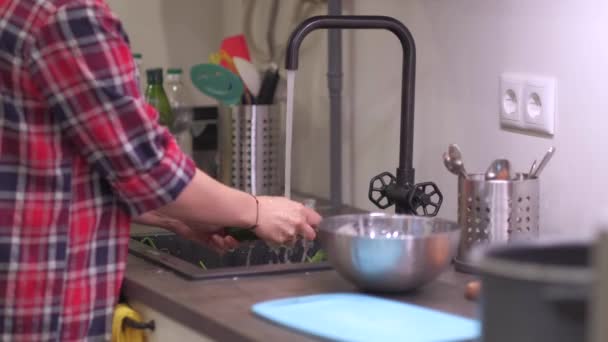 Mladá žena myje zeleninu v kuchyňském dřezu — Stock video