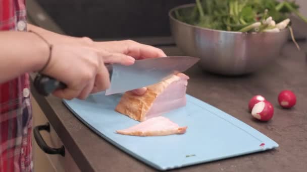 Молодая домохозяйка режет кусок копченой свинины — стоковое видео