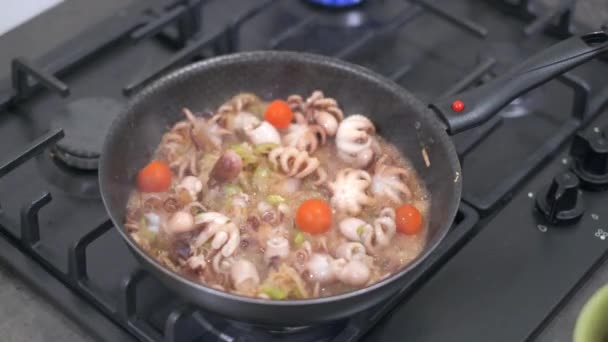 Woman drops tomatoes on fried pan with seafood — Stock Video