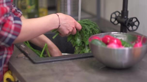 Jovem dona de casa lava verdes na pia da cozinha — Vídeo de Stock