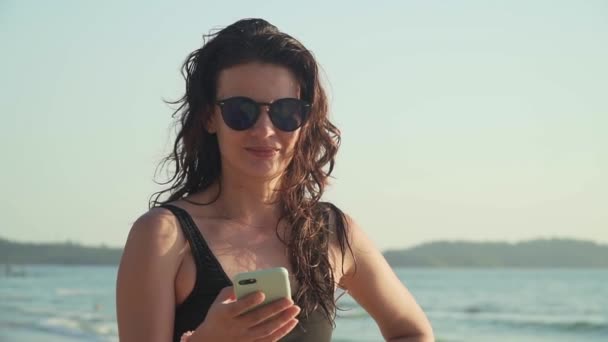 Mujer feliz hace una llamada telefónica y habla en la playa — Vídeo de stock