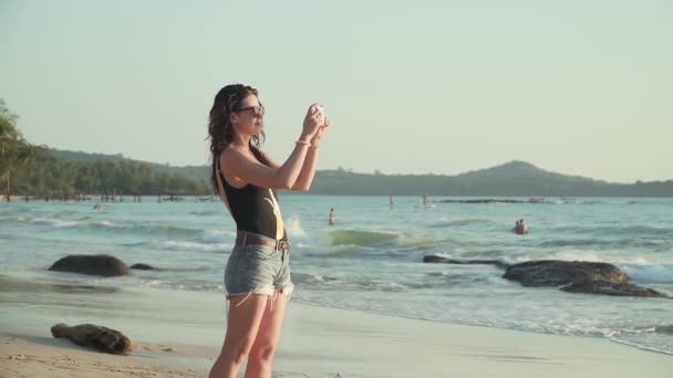 Mujer feliz toma fotos del atardecer sobre el mar — Vídeos de Stock