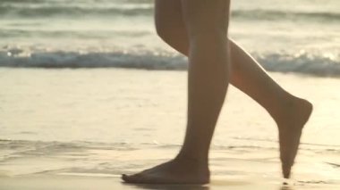 Gün batımında sahilde yürüyen kadın bacakları yakın çekim