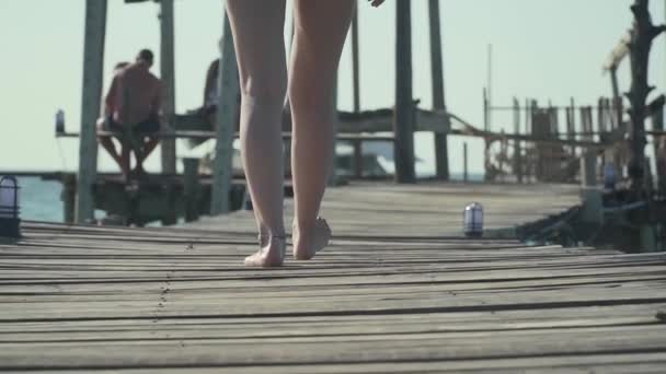 Kobieta idzie na drewnianym molo na tropikalnej plaży — Wideo stockowe