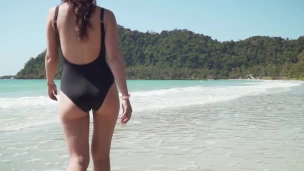 Молода жінка йде вздовж піщаного пляжу біля моря — стокове відео