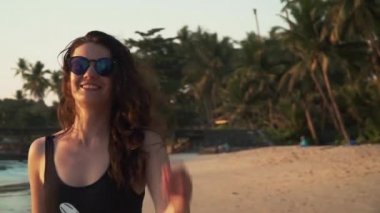 Mutlu kadın gün batımında sahilde tatil sahiptir