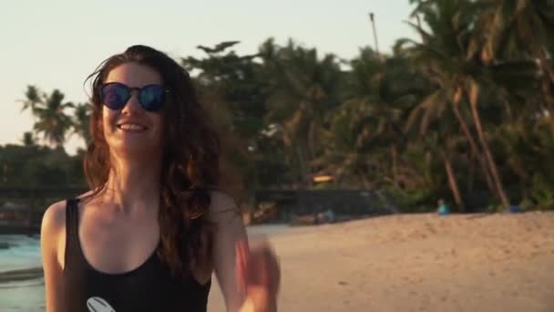 Щаслива жінка насолоджується відпочинком на пляжі на заході сонця — стокове відео