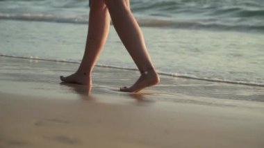 Gün batımında sahilde yürüyen kadın bacakları yakın çekim