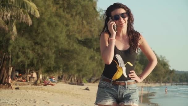 Mujer feliz hace una llamada telefónica y habla en la playa — Vídeo de stock