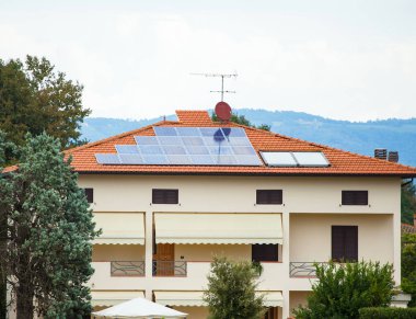Fotovoltaik güneş paneli çatıda. Arka plan gri bulutlu gökyüzü.
