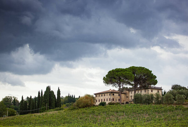 Tuscan hillside panorama with cloudy sky and typical local habitation.