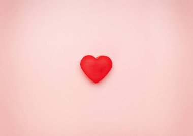 Pembe bir arka plan merkezinde kırmızı kalp.