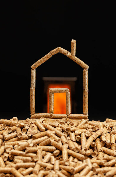Miniature house made with wood pellets. Heating concept with combustion chamber in the background.