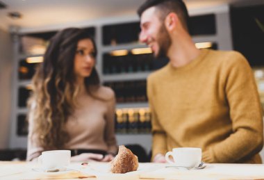 Bir kruvasan kahvaltı sırasında odak. Arka plan genç çift gülümseyen.