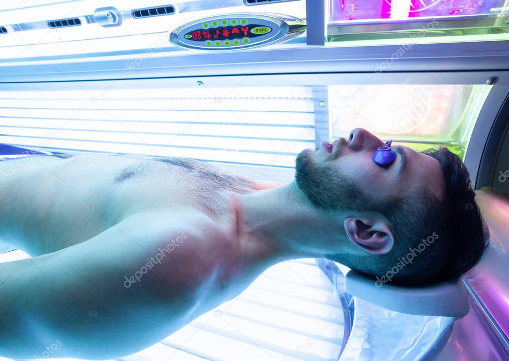 Young Thin Man At Solarium In Beauty Salon. Full tanning bed.