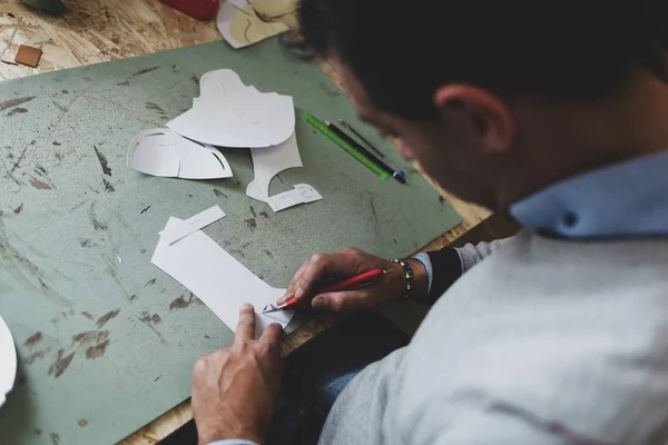 Schoen ontwerper werkt met papier modellen voor het snijden van leder. — Stockfoto