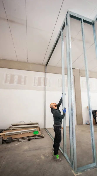 Werknemer bouwt een muur gipsplaat. — Stockfoto