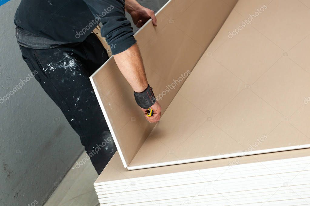 Worker builds a plasterboard wall.