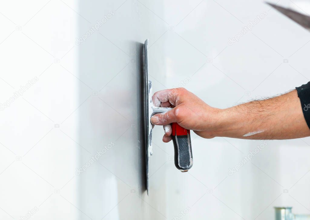 worker plastering gypsum board wall.