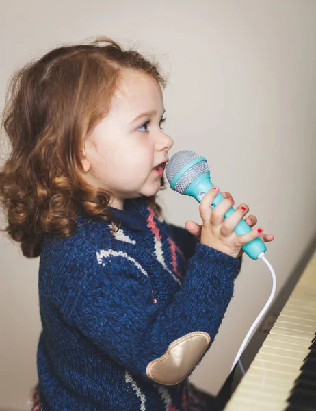 Flicka småbarn, piano och leksak mikrofon. — Stockfoto