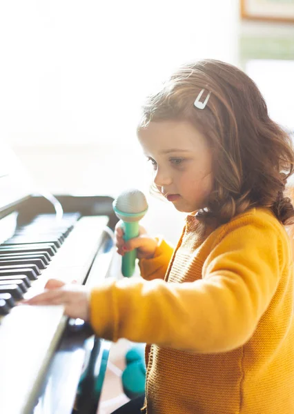 Menina criança brinca com piano e brinquedo microfone . — Fotografia de Stock