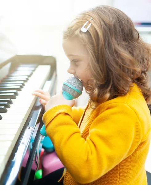 Girl toddler plays with piano and toy microphone. — Stock Photo, Image