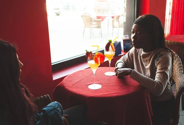 Dois amigos conversam dentro de um bar enquanto bebem um cocktail . — Fotografia de Stock