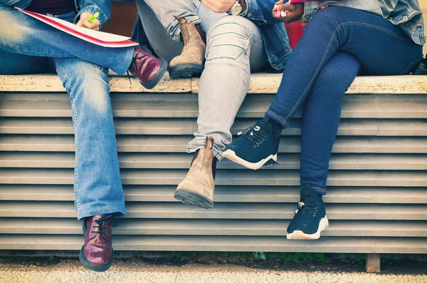 Gambe di studenti seduti su una panchina . — Foto Stock