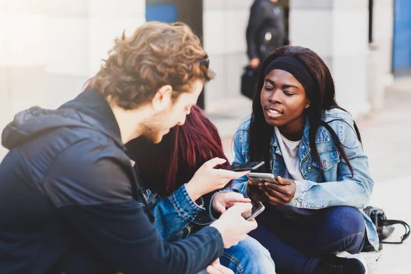 Tre unga människor som använder mobiltelefon. — Stockfoto