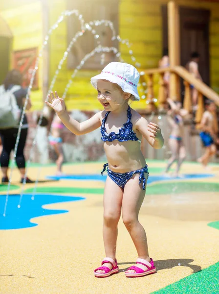 Счастливая маленькая девочка играет через фонтан . — стоковое фото
