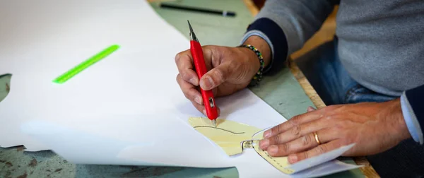 Schoen ontwerper werkt met papier modellen voor het snijden van leder. — Stockfoto