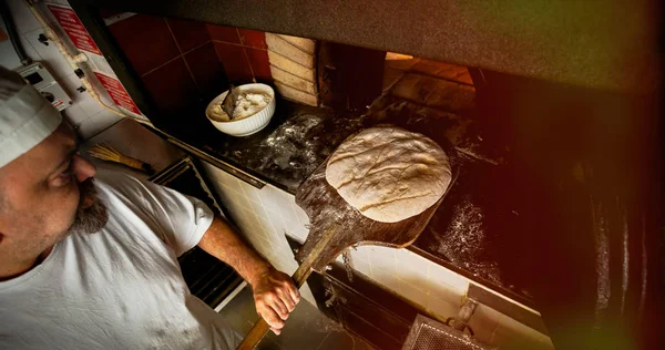 Produktion av bröd med en vedeldad ugn i ett bageri. — Stockfoto