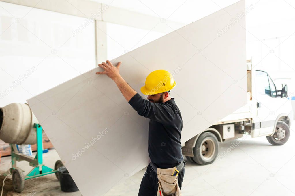 Worker builds a plasterboard wall.