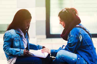 İki genç kadın bir bankta çalışma.