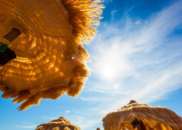 Blick von unten auf schöne reetgedeckte Sonnenschirme am Strand. — Stockfoto