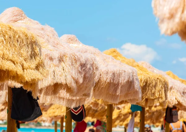 Strand mooie rieten parasols en turquoise zee. — Stockfoto