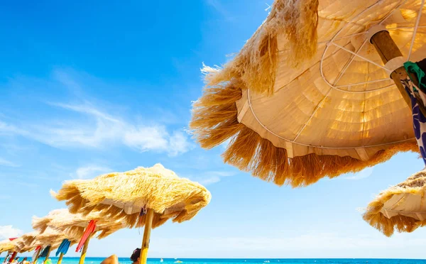 Plaża piękne kryte strzechą parasole i turkusowe morze. — Zdjęcie stockowe