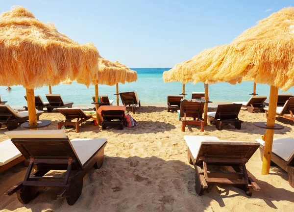 Strand schöne reetgedeckte Sonnenschirme und türkisfarbenes Meer. — Stockfoto