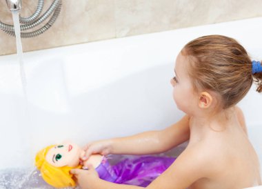 Kadın bebek bir banyo alır ve plastik oyuncaklar ile oynar