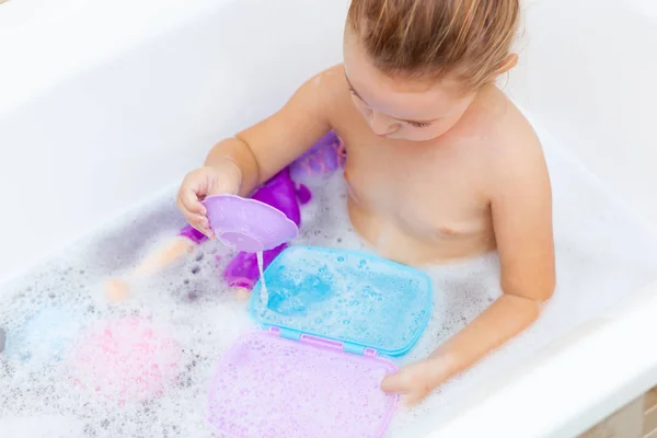 Female toddler takes a bath and plays with plastic toys — Stock Photo, Image