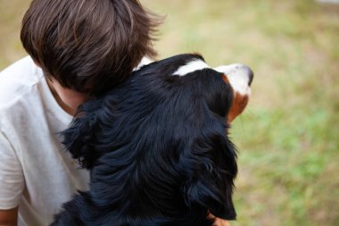 Child embraces his dog resting his head as a sign of affection and comfort. clipart