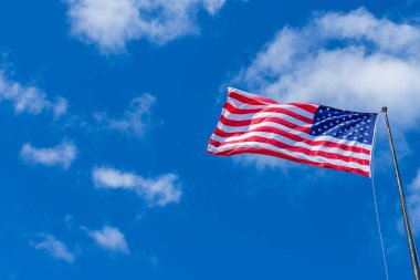 Amerikan bayrağı ile bulutlu mavi gökyüzü güneşli bir günde sallayarak