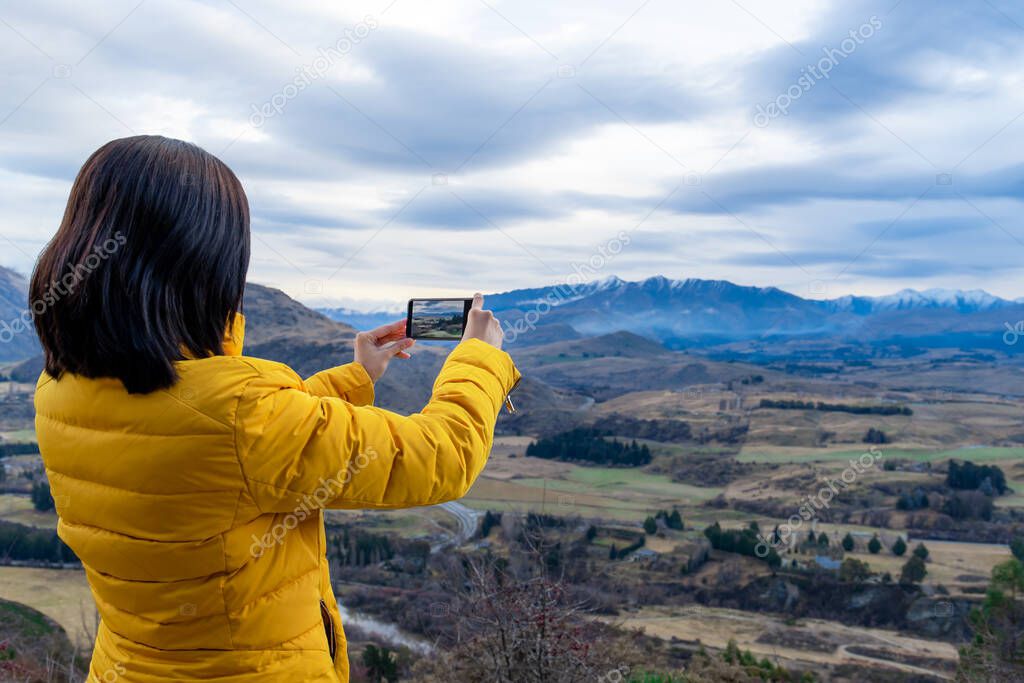 Asian tourist woman taking photo with mobile phone in Queenstown South Island New Zealand