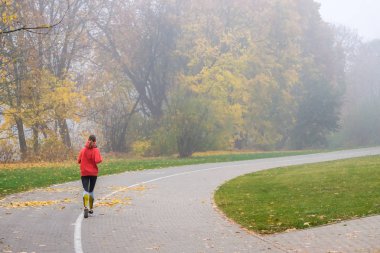 Vilnius, Litvanya - 21 Ekim, 2018: sisli şehir parkı ile sabah çalışan kadın.